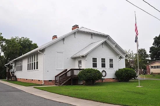 White community building with a flagpole and lawn